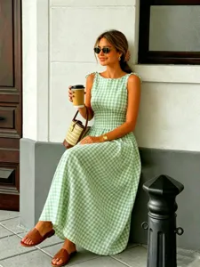 Detail shot of a green and white gingham sleeveless midi dress with smocked waist.