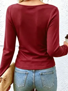 Detail shot of a solid color long sleeve top worn by a model standing against a white wall.