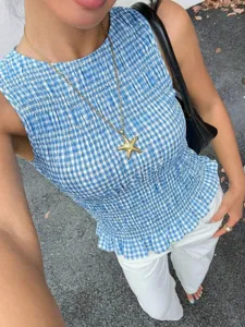 Dettaglio del top smanicato arricciato a quadri vichy blu e bianco, primo piano del tessuto.
