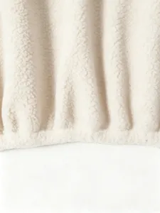 Close-up detail of soft cream teddy fleece fabric, showing cozy texture and hem design.