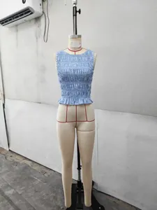 Vista dettagliata del top corto smock a quadri blu e bianchi con eleganti finiture.