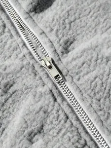 Close-up detail of grey lamb fleece jacket zipper, showing soft texture and metal pull.