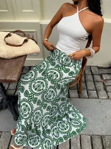 Detailed shot of bohemian green print long skirt paired with white halter top in outdoor scene.