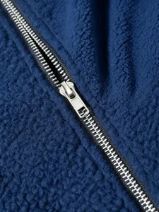 Close-up detail of dark blue fleece jacket with metal zipper, showcasing soft fluffy texture.
