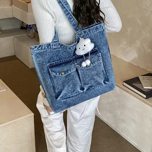 Detail view of casual denim tote bag with front pockets and cute cloud pendant for daily use.