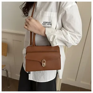 Vista dettagliata di una elegante borsa a tracolla marrone in pelle con chiusura metal.