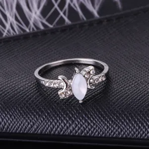 Close up view of silver ring featuring white marquise opal stone with crescent moon and stones.