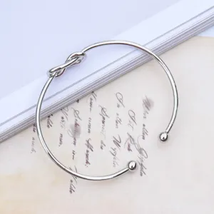 Silver tone metal cuff bracelet with minimalist knot design and ball ends, open bracelet.