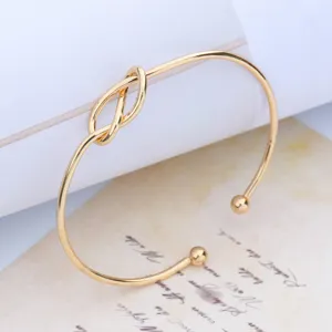 Gold color minimalist 8-shape knot open bangle bracelet, elegant fashion alloy wrist detail.