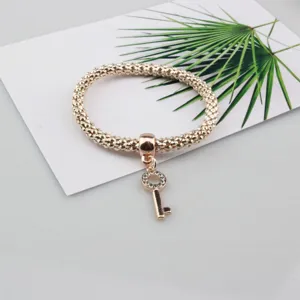 Primer plano de la pulsera elástica de cadena tipo popcorn en oro rosa con colgante de llave de strass.