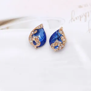 Gedetailleerde close-up van elegante blauwe druppel kristal pauw oorbellen met goud.