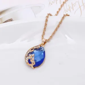 Detailopname van een prachtige blauwe druppel kristallen ketting met elegant gouden pauwontwerp.