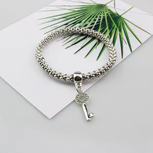 Vista de detalle de una pulsera elástica de cadena popcorn plateada con colgante de llave.