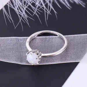 Detailed view of a simple minimalist opal ring, silver-colored alloy band with white gemstone.