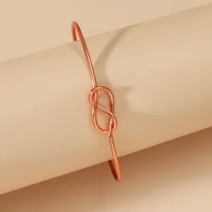 Close-up of a minimalist rose gold infinity knot metal open bracelet, elegant daily jewelry detail.