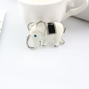 Closeup of exquisite white elephant brooch featuring enamel, sparkling rhinestones, and blue eye.