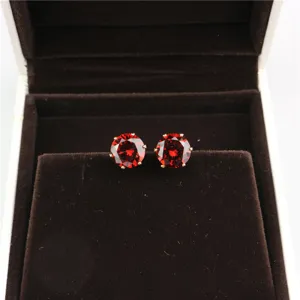 Detailed view of round 8mm red zircon stud earrings in a brown velvet jewelry box.