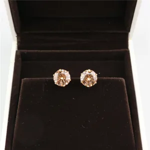 Detail view of round champagne cubic zirconia stud earrings placed inside dark velvet box.