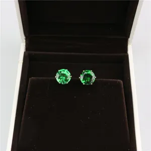 Close-up view of elegant round 8mm green zircon stud earrings displayed inside luxury jewelry box.