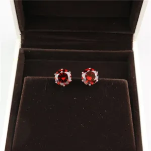 Close-up detail shot of red round 8mm cubic zirconia stud earrings in a luxury brown velvet box.