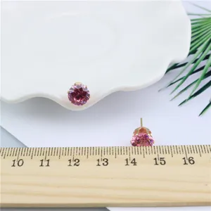 Close-up detail of shiny pink zircon round stud earrings with size reference ruler.