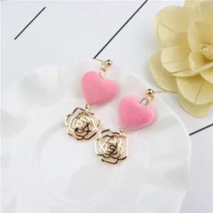 Close-up detail of sweet pink fuzzy heart and gold hollow rose zircon earrings, elegant style.