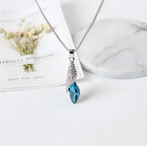 Detailfoto van een zilveren druppelblauwe kristallen ketting met sprankelende strass-steentjes.