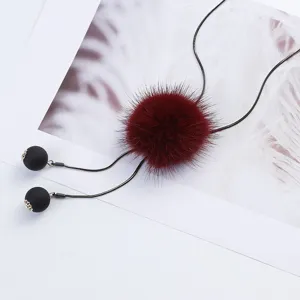 Close-up of dark red mink fur pom-pom pendant on long sweater chain with black beads.