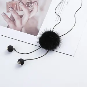 Close-up detail of a black mink fur pom pom sweater chain necklace with snake chain.