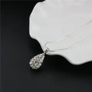 Detailed view of the sparkling rhinestone pave teardrop pendant necklace on white plate.