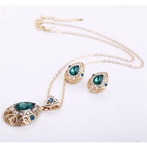 Close up of crystal teardrop pendant necklace and matching earrings set detailing gold setting.