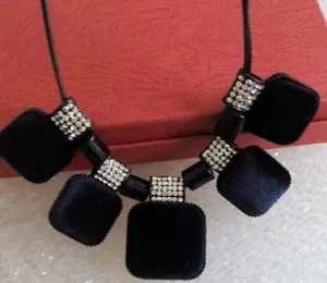 Détail en gros plan d'un collier pendentif carré en velours noir avec des strass.
