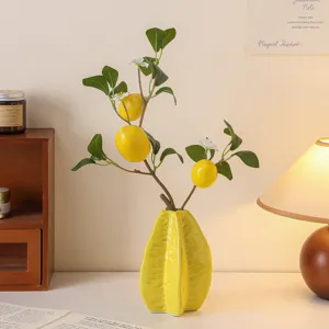 Ceramic starfruit vase with artificial lemon tree branches, artistic desktop floral decor.