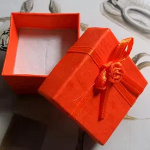 Caja de regalo de joyería naranja con lazo, ideal para anillos y accesorios pequeños.