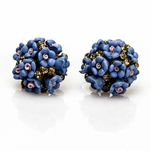 Detailopname van blauwe keramische bloem oorknopjes oorbellen met fonkelende strass steentjes.