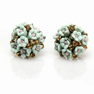 Detailopname van de fijne mintgroene keramische bloem strass oorknopjes in cluster.