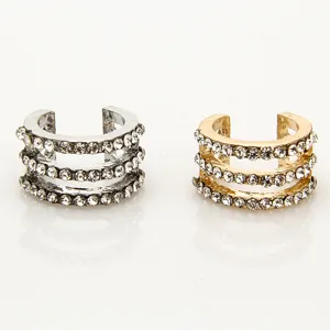 Gedetailleerde close-up van meerrijige strass metalen oorclips en knokkelringen in zilver en goud.