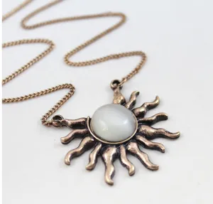 Vintage bronze sun pendant necklace detail, retro style sweater chain with white stone accent.