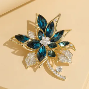 Exquisite detail view of a gold-plated flower brooch featuring deep blue crystal and sparkling rhinestones.