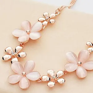 Close-up detail of a delicate rose gold flower necklace with pink cat eye stone petals.