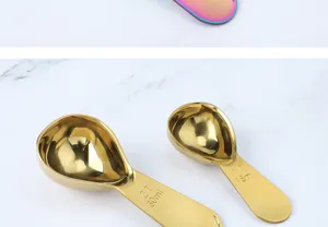 Stainless steel measuring spoon detail view, showing clear capacity scales and smooth golden finish.