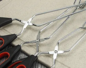 Stainless steel kitchen food tongs detail shot, featuring non-slip handles for cooking.