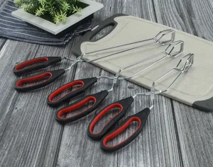 Stainless steel kitchen food tongs detail view, ergonomic black red handles for secure grip.