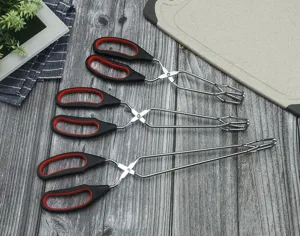 Detailed view of kitchen food tongs with black and red handles on wooden background.