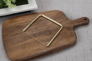 Gros plan du tranche-fromage à fil doré sur planche à découper en bois, outil de cuisine.