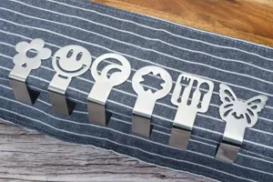 Dettaglio di clip per tovaglie in acciaio inossidabile con ritagli creativi come fiori e farfalle.