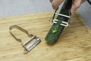 Stainless steel vegetable peeler and julienne grater, dual-function fruit peeling gadget.