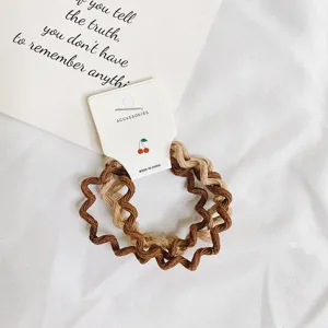 Close-up detail van golvende haarscrunchies in bruin en beige, elastische haaraccessoires.