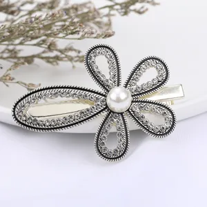 Close-up detail of rhinestone flower hair clip, shiny crystal petals with pearl center.