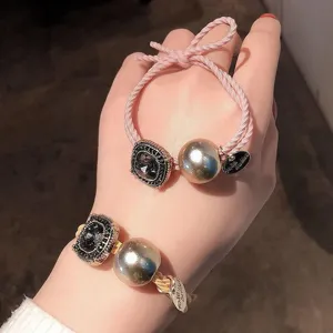 Detailed close-up view of elegant hair ties with metallic beads and rhinestone square charms.